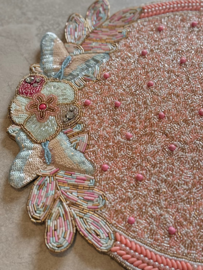 Close-up of an intricately beaded and embroidered butterfly design on a textured surface.